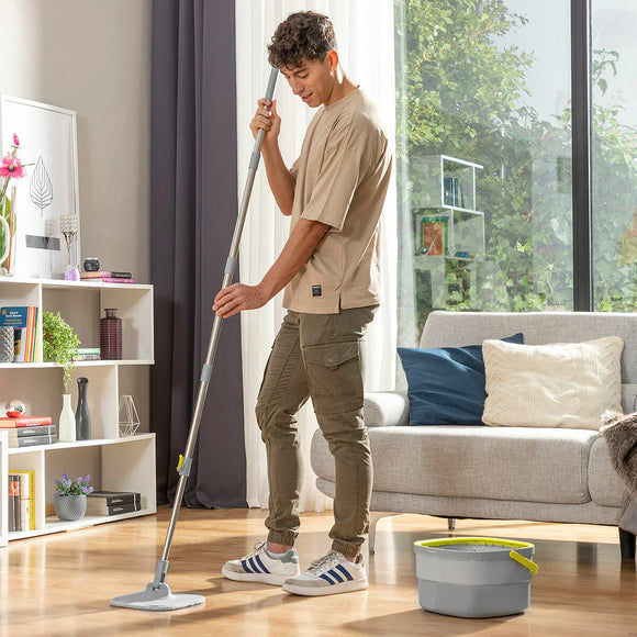 Uomo mentre pulisce il pavimento con un mop in un soggiorno moderno e luminoso
