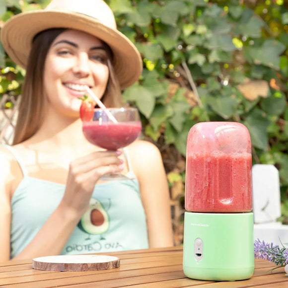 Frullatore portatile per smoothie accanto a una donna sorridente che gusta una bevanda alla frutta