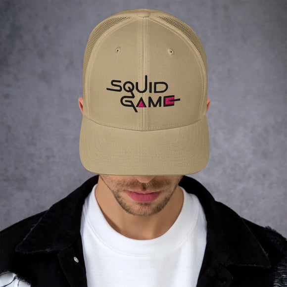 Cappellino Squid Game originali con logo iconico su sfondo grigio, celebrando il fenomeno culturale