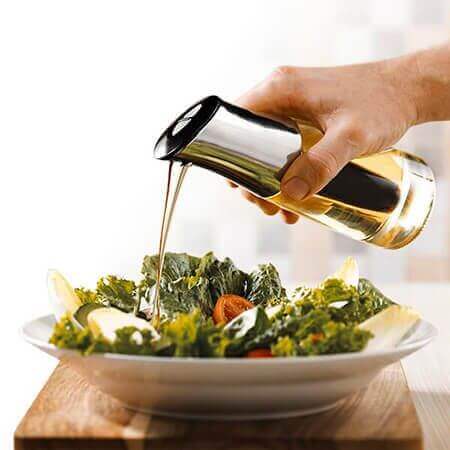 Distributore di olio su un'insalata fresca con ingredienti di qualità per piatti gourmet