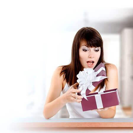 Donna sorpresa mentre apre un regalo innovativo dalla collezione idee regalo donna innovative