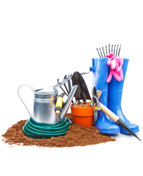Collezione di attrezzi da giardino con annaffiatoio, guanti e stivali in gomma su un letto di terra