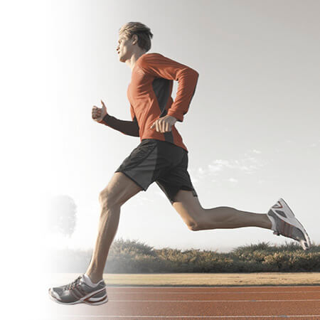 Uomo che corre su una pista con abbigliamento sportivo tecnico per running e atletica