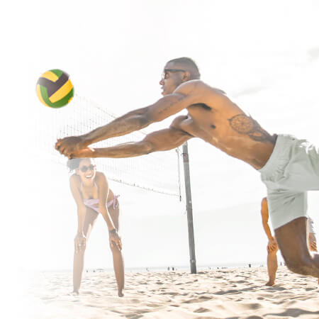 Giocatori di pallavolo sulla spiaggia che si divertono con un pallone colorato in un'atmosfera estiva