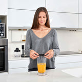 Donna che utilizza un frullatore multiuso potente nero per preparare un frullato in cucina moderna