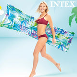 Donna sorridente in bikini che tiene un materassino gonfiabile Intex tropicale con motivi floreali vivaci