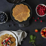 Macchina per waffle in acciaio inox con waffle dorati serviti con frutta fresca e decorazioni