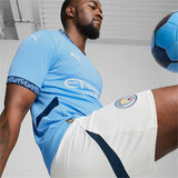 Giocatore che indossa la maglia Manchester City 2024 2025 originale con pantaloni bianchi e pallone da calcio