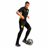 Giocatore che indossa Puma pantaloncini calcio adulto neri, con logo Borussia Dortmund, mentre calcia un pallone