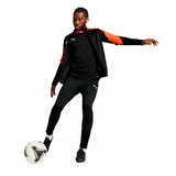 Tuta Puma uomo nera indossata da un atleta mentre calcia un pallone da calcio