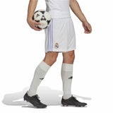 Calciatore che indossa i short calcio ufficiali Real Madrid 2023 mentre tiene un pallone Adidas